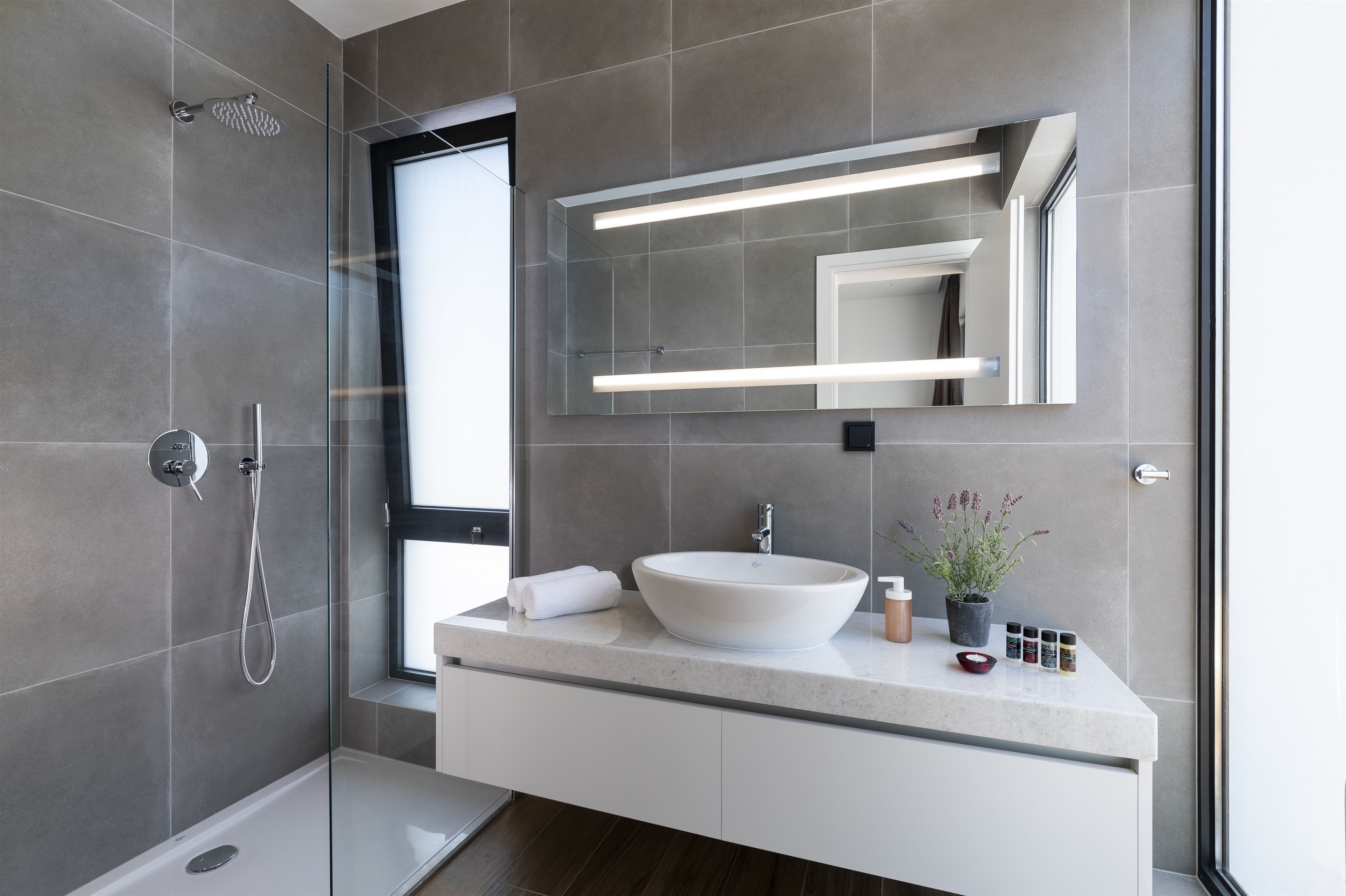 Une salle de bain moderne avec une douche à parois de verre, un lavabo blanc et un grand miroir.