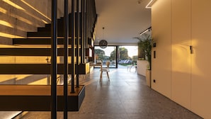 A modern interior with a staircase, a dining area, and a view through large windows. - Momentum Villas (Rhodes)