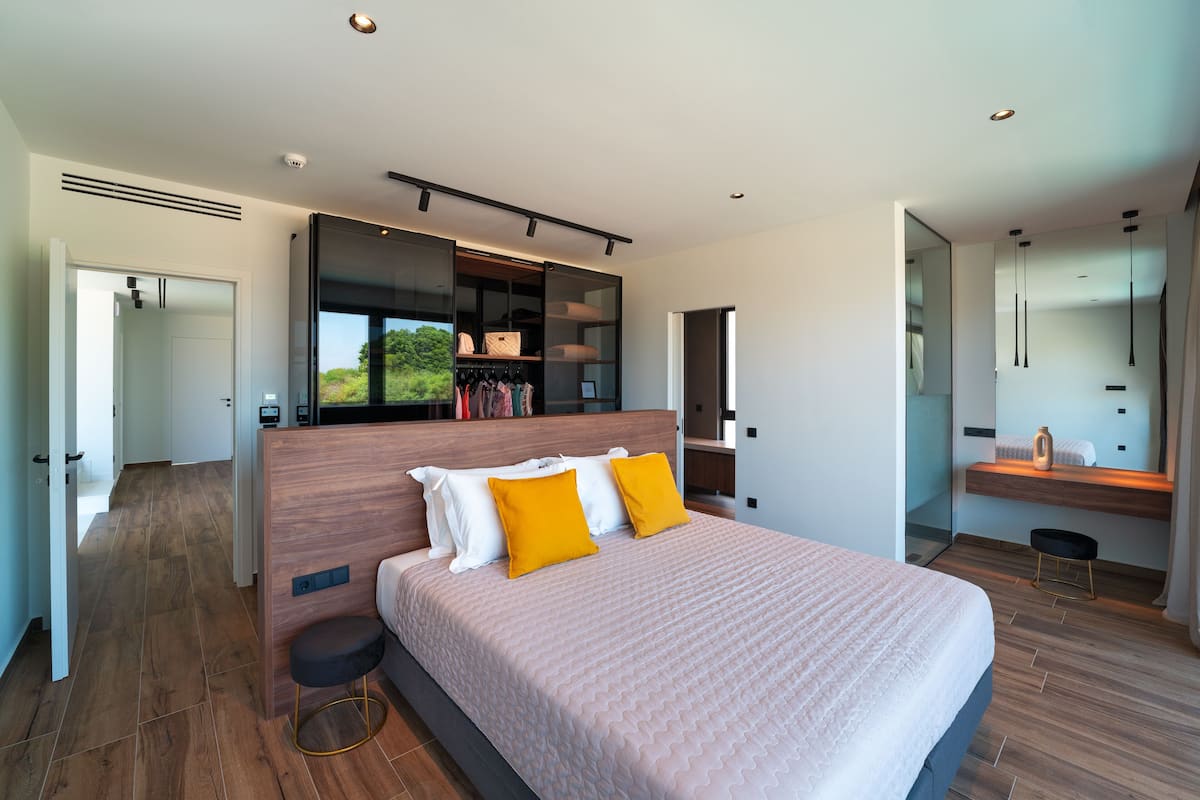 Ein modernes Schlafzimmer mit einem großen Bett, Einbauschrank und Blick auf Grün.