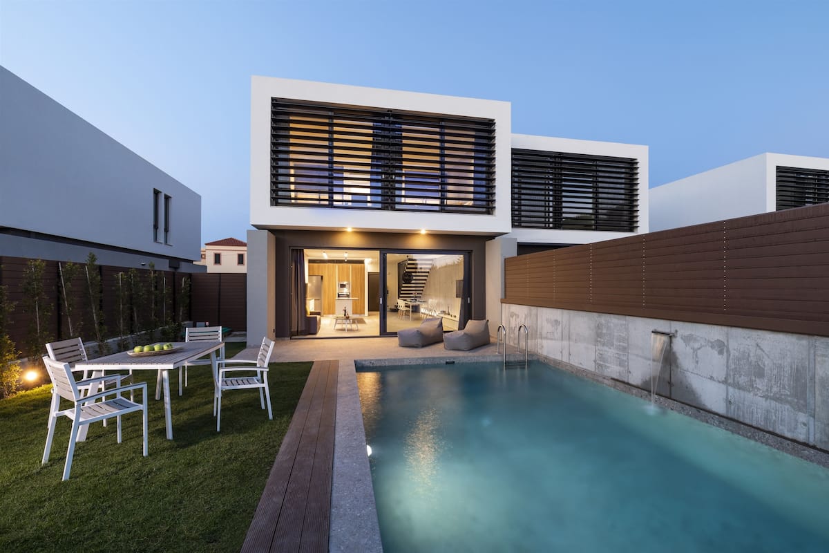 Ein modernes Haus mit Swimmingpool, einer Terrasse und Gartenmöbeln sowie einem hellen Innenraum.