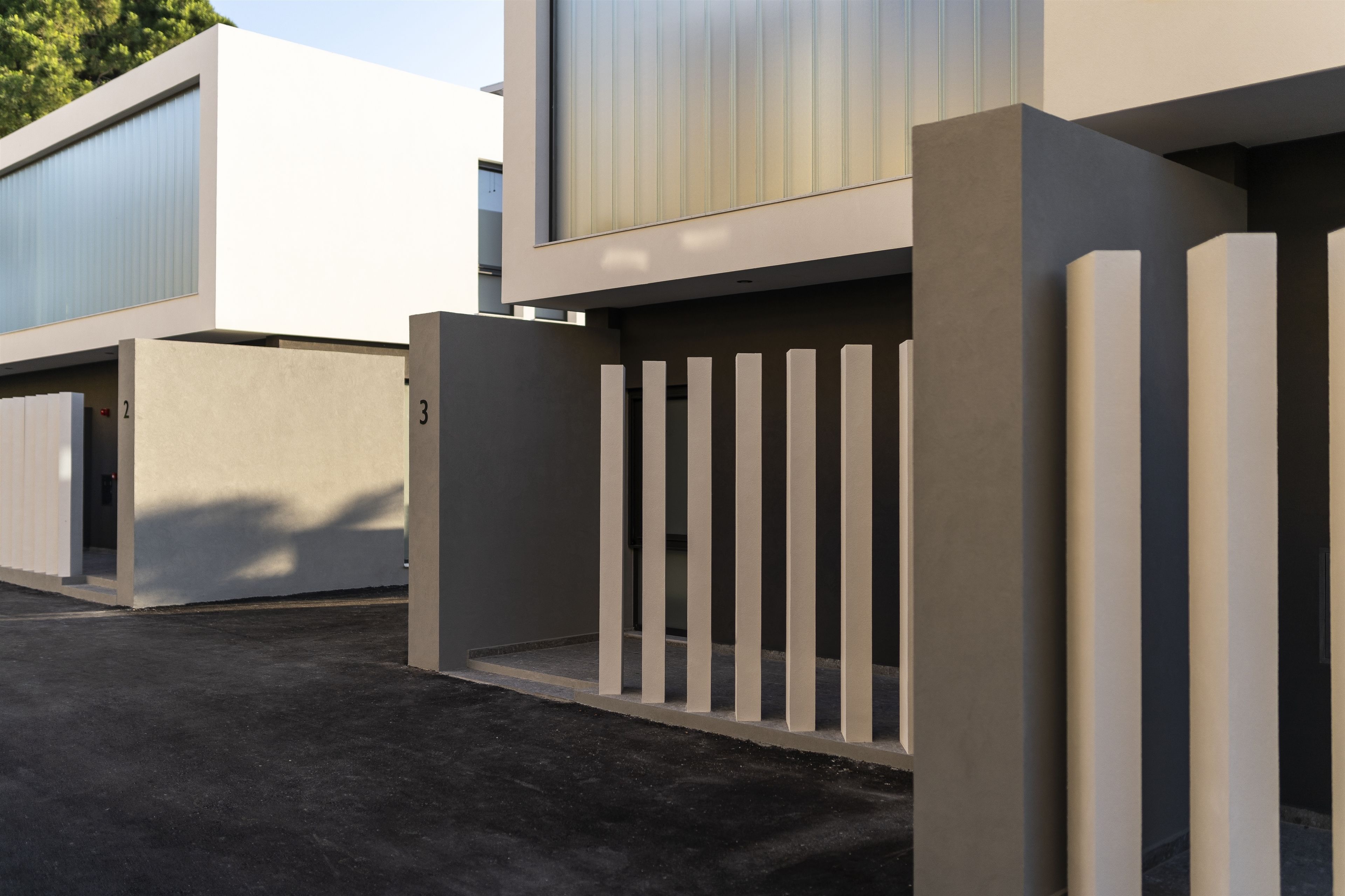 Un edificio moderno con entrada protegida y un camino de concreto que lleva a las puertas.