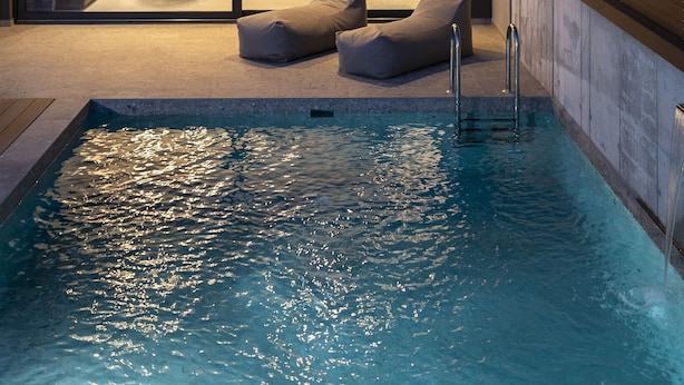 A modern two-story house with a swimming pool, a kitchen, and a dining area visible through large glass doors. - Momentum Villas (Rhodes)