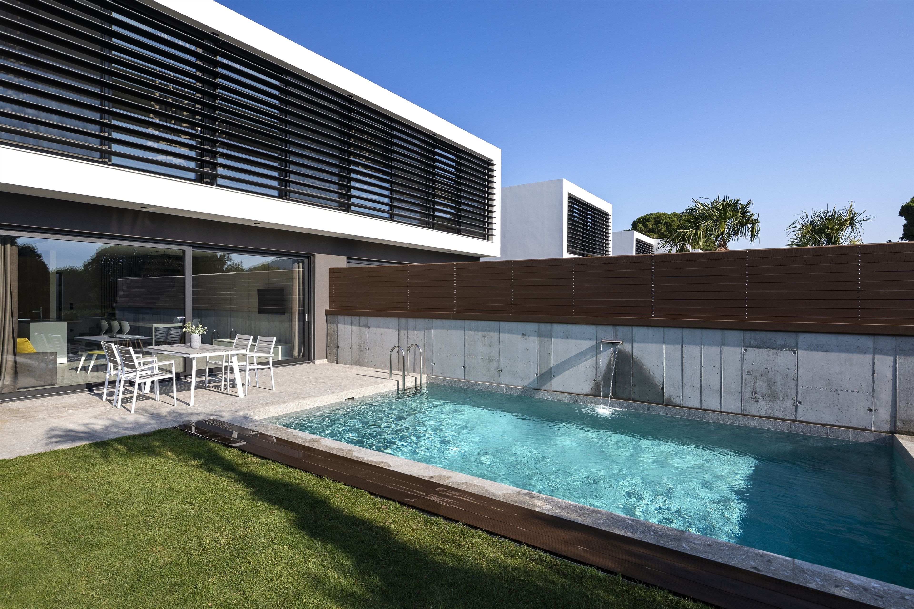 A modern outdoor pool area with a built-in seating area and a clear blue pool.