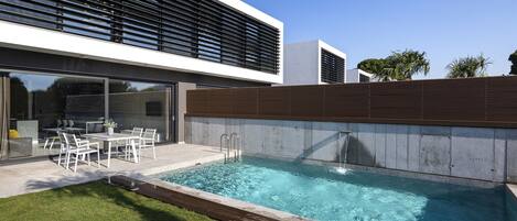 A modern outdoor pool area with a built-in seating area and a clear blue pool.