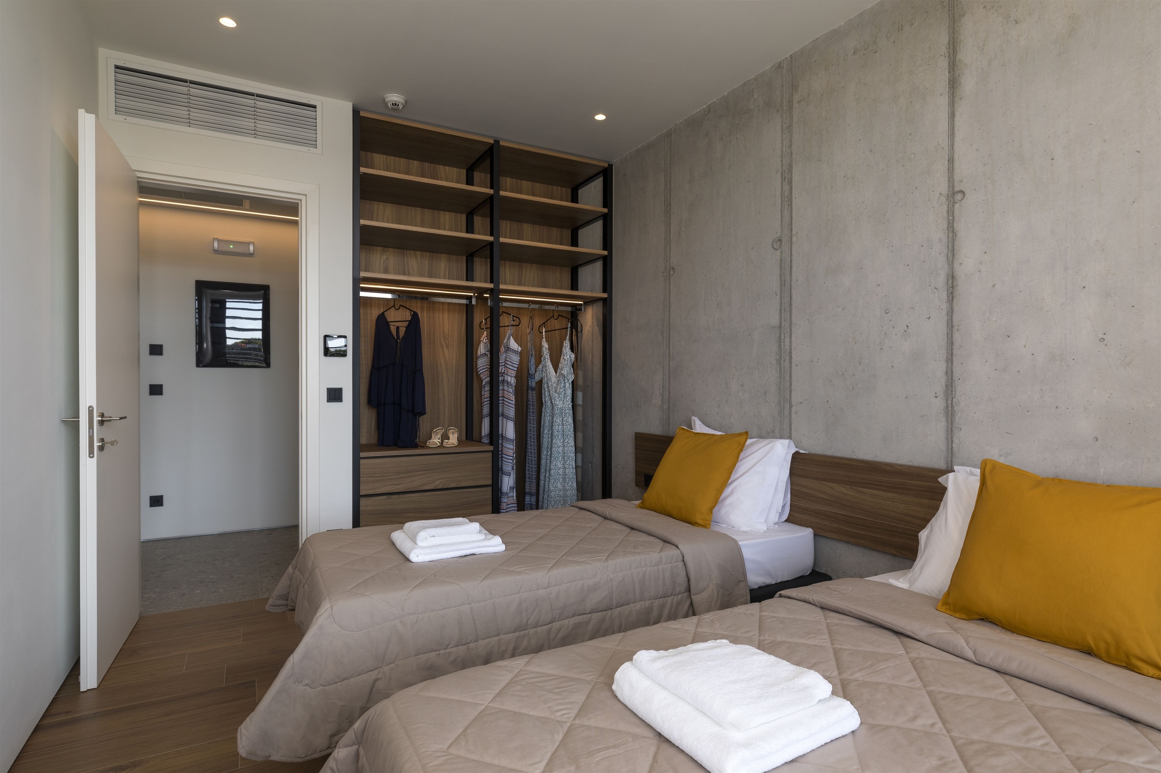 A hotel room with two beds, a wardrobe, and a bathroom.