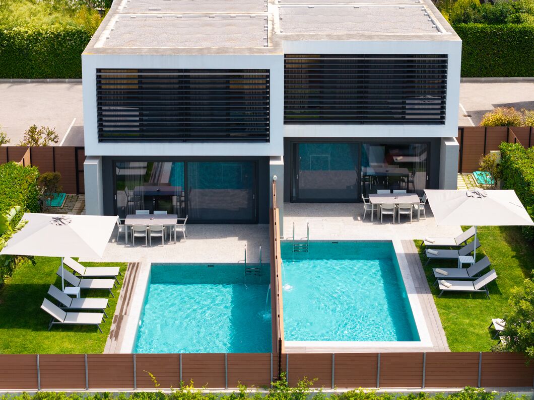 Une maison moderne à deux étages, dotée d’une piscine, d’un espace extérieur aménagé et d’un jardin bien entretenu.