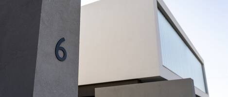 A modern building with a large number '6' on a grey wall.