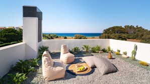 A rooftop terrace with seating, a view of the sea, and a cactus garden. - Momentum Villas (Rhodes)
