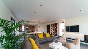 A modern living room with a grey sofa, yellow cushions, a white coffee table, and a beige bean bag. - Momentum Villas (Rhodes)