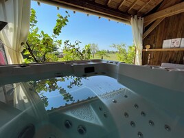 Uma banheira de hidromassagem com vista para o verde ao redor e teto de madeira.