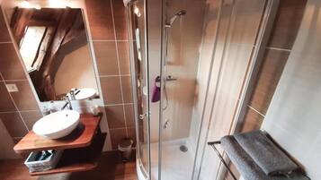 A bathroom with a glass-enclosed shower, a sink with a wooden countertop, and a towel rack.