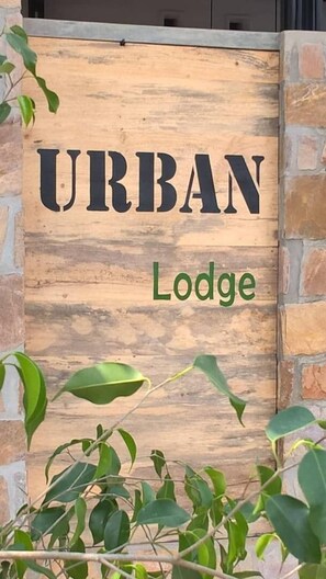 A wooden sign with "URBAN Lodge" written on it, surrounded by greenery. - Urban Lodge (Bujumbura)