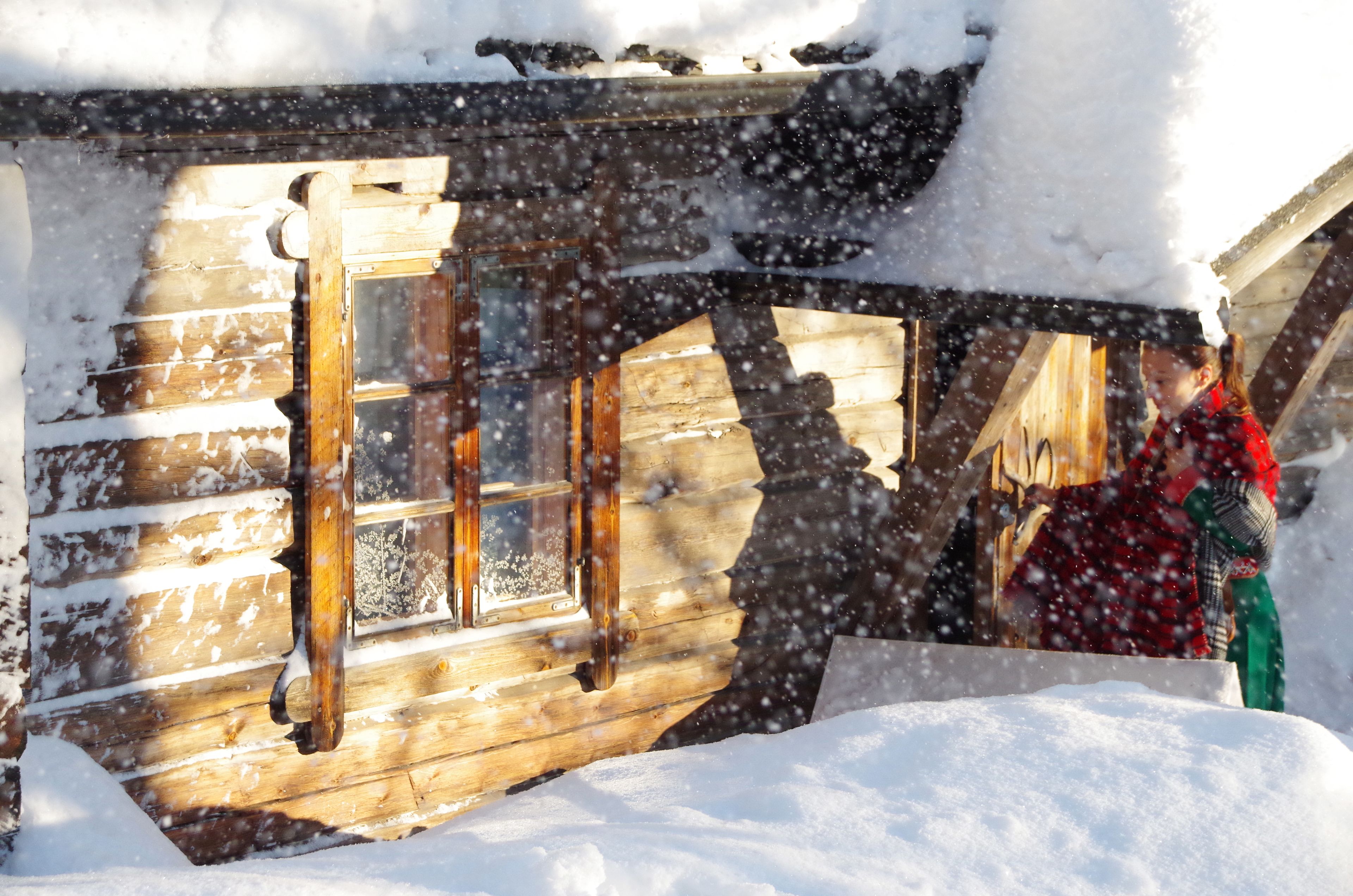 Eine Holzhütte mit Fenster und Tür, umgeben von Schnee.