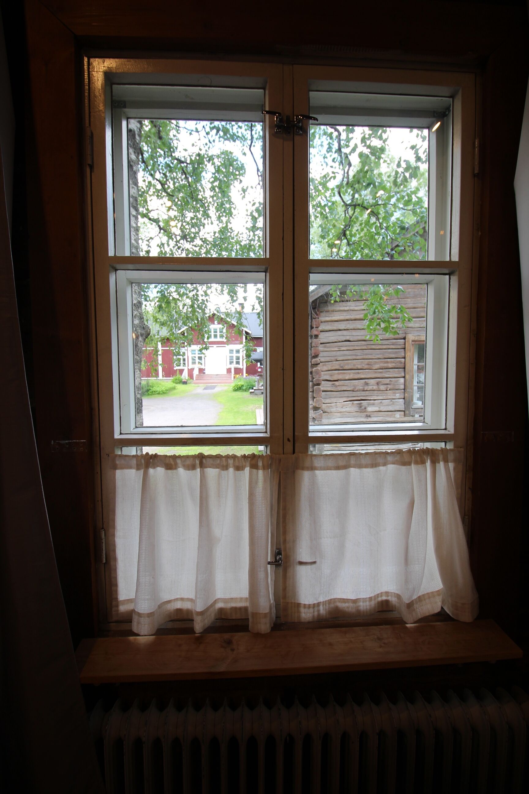 Una ventana con vista a un edificio rojo y una valla de madera.