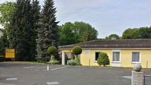 A yellow building with a sign reading "Hotel Merkur." - Hotel Merkur Garni (Giesen)