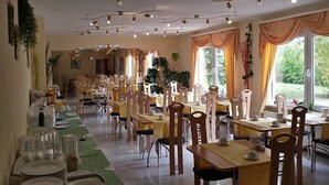 A spacious dining area with multiple tables and chairs, arranged in a linear fashion. - Hotel Merkur Garni (Giesen)