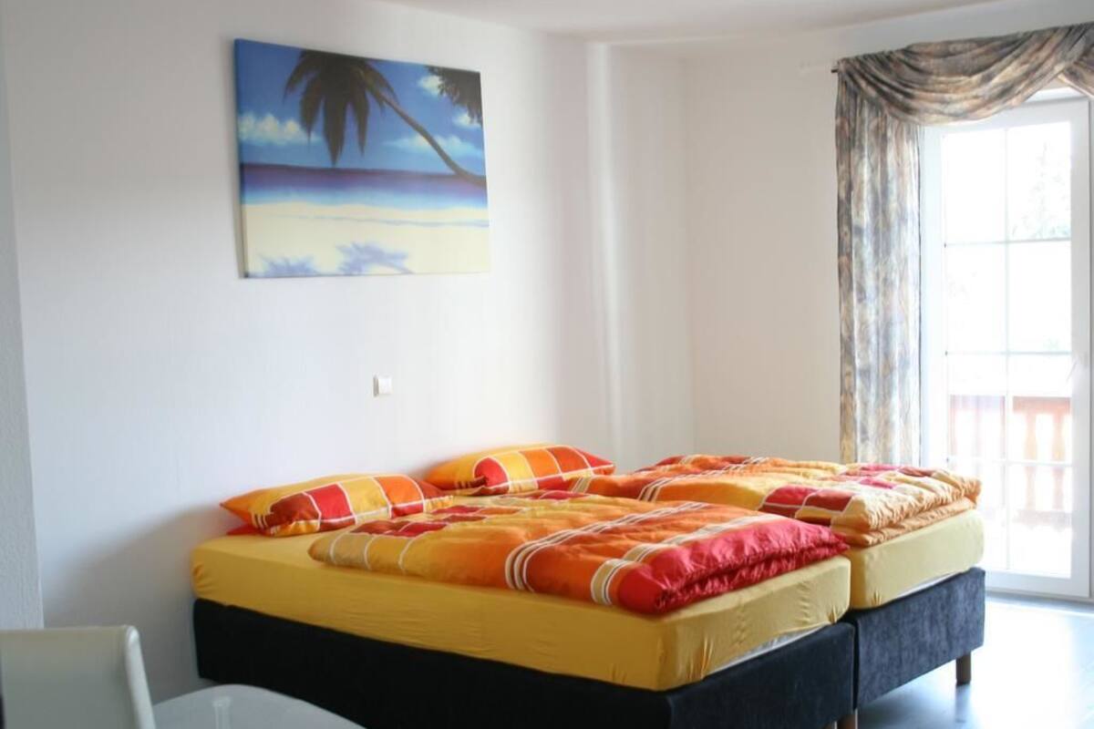 Un dormitorio con una cama, una silla y un cuadro en la pared.