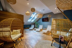 A room with wicker chairs, a wooden wall, and a ceiling with woven light fixtures.