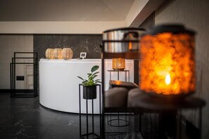 A reception area with a white counter, a potted plant, and a modern lamp.