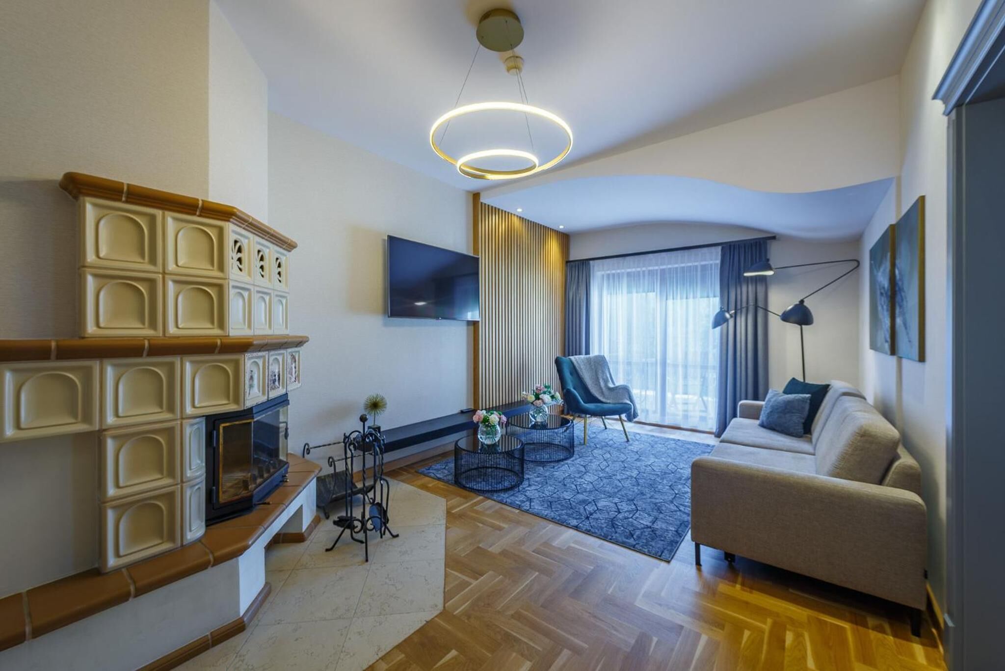 Uma sala de estar moderna com lareira, sofá, televisão e uma grande janela com cortinas.