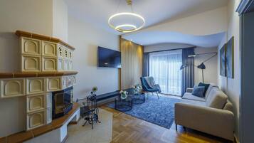Uma sala de estar moderna com lareira, sofá, televisão e uma grande janela com cortinas.