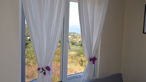 A window with white curtains and a view of a landscape. - Kaye Coco (Choiseul)