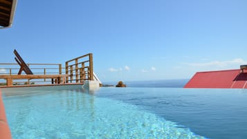 Una piscina al aire libre, sillones reclinables de piscina