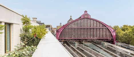 A train station with a prominent pink arch structure and multiple tracks.