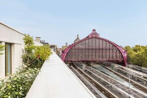 Una estación de tren con una llamativa estructura en forma de arco rosa y múltiples vías.