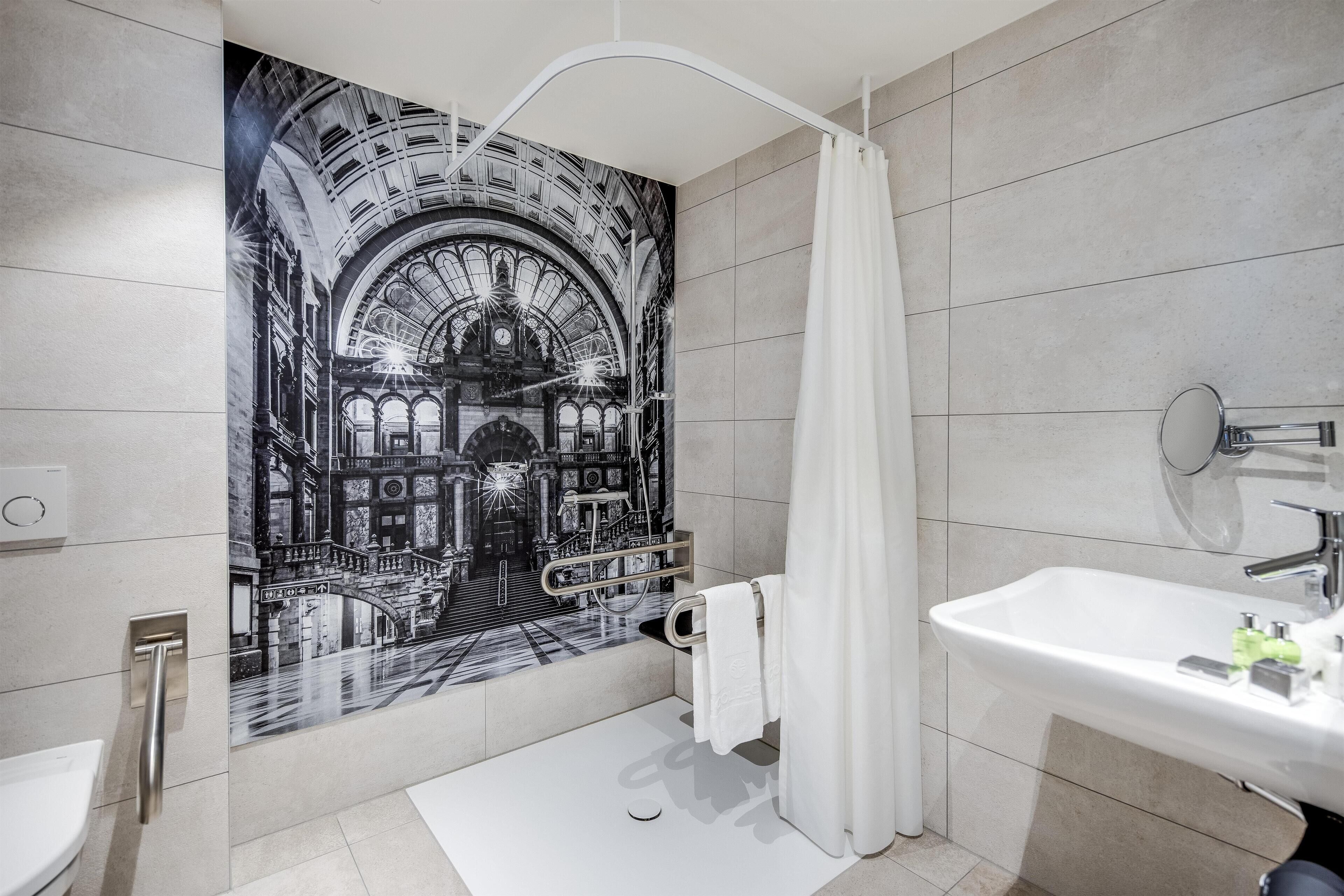 A modern bathroom with a large mural of a historical building, a white sink, and a shower curtain.