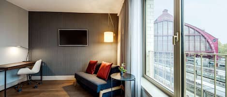 A hotel room with a bed, a desk, a sofa, and a TV.