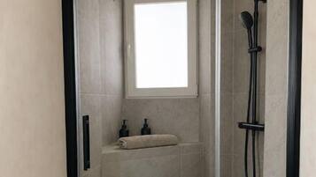 Una cabina doccia senza barriere, con finestra, soffione a mano e doccetta.