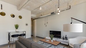 A modern living room with a sofa, coffee table, TV, and decorative items. - Brand New Stunning Unit Downtown (Dallas)