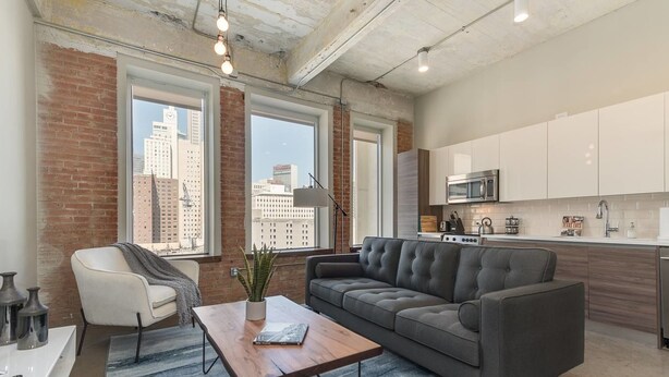 A modern apartment with a living area, kitchen, and large windows offering city views. - Brand New Stunning Unit Downtown (Dallas)