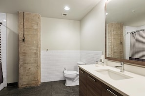 A bathroom with a white toilet, a sink with a mirror, and a shower area. - 3 Bedroom - Best Location, Pool, Gym & Parking (Dallas)