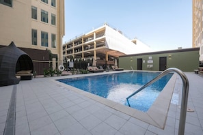 An indoor swimming pool with a tiled floor, lounge chairs, and a covered seating area. - Modern 1bd in the Core of Downtown (Dallas)