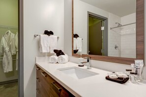 A modern bathroom with a large mirror, white sink, and wooden cabinetry. - 3 Bedroom Unit in Downtown Dallas with Pool & Gym (Dallas)