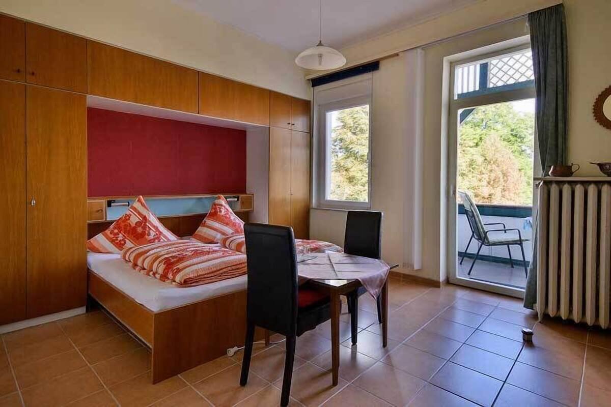 Un dormitorio con cama, una mesa, sillas, un ventanal y vistas al exterior.