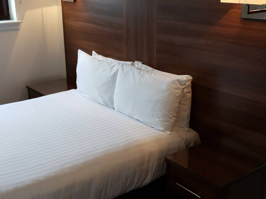 Een hotelkamer met een groot bed, twee nachtkastjes en twee wandlampen.