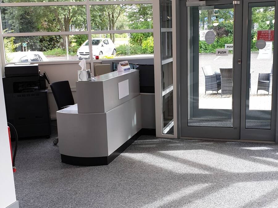 A reception area with a reception desk, a printer, and a glass door leading outside.