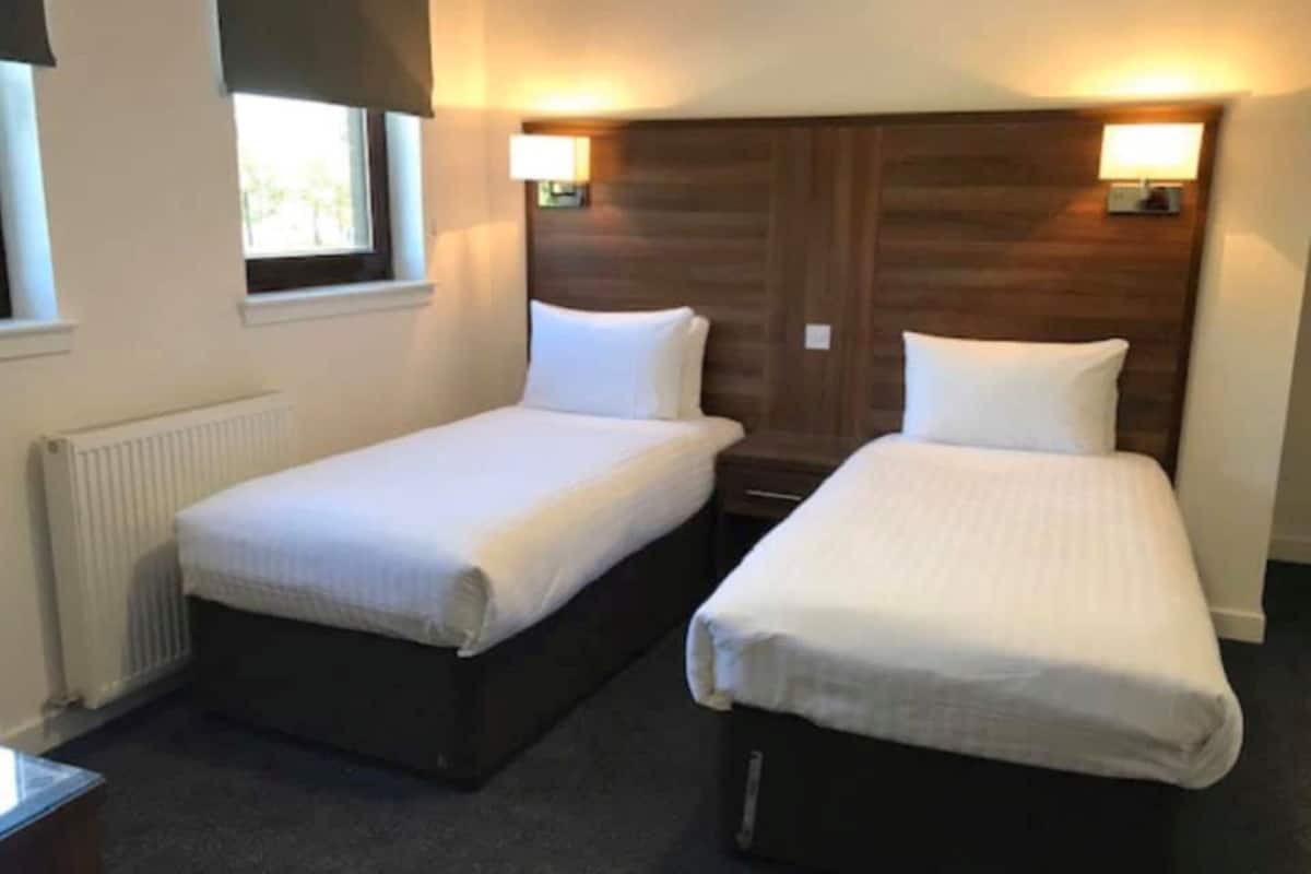 Two single beds with headboards, a window, and a radiator.