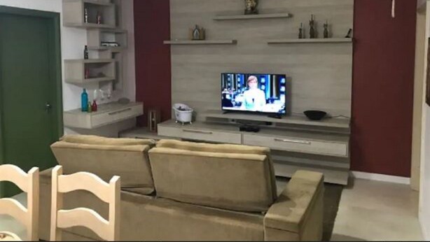 Sala de estar com sofá, televisão e estantes.