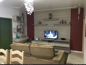 A living room with a sofa, TV, and shelves.