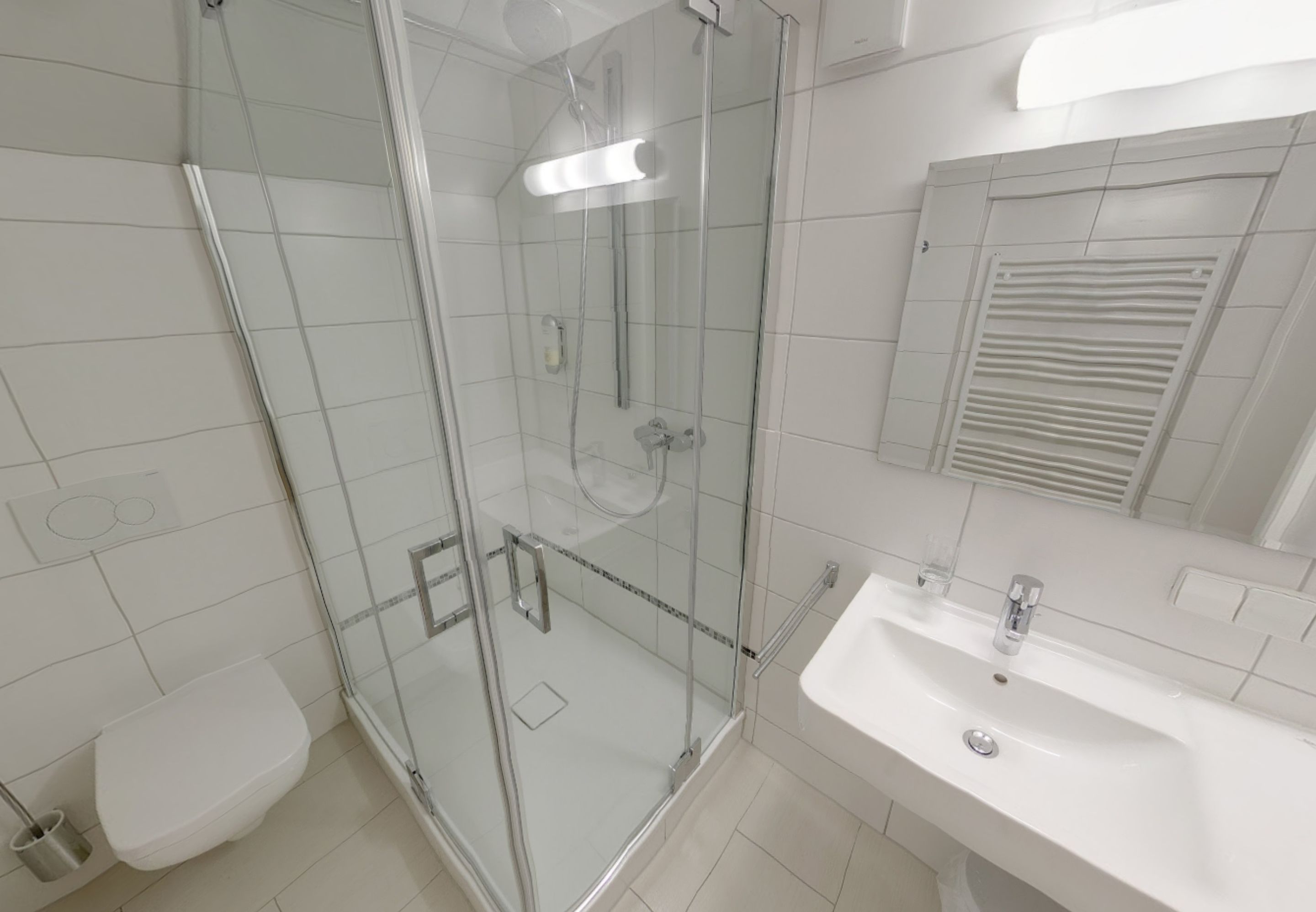 A modern bathroom with a glass-enclosed shower, a white sink, and a toilet.