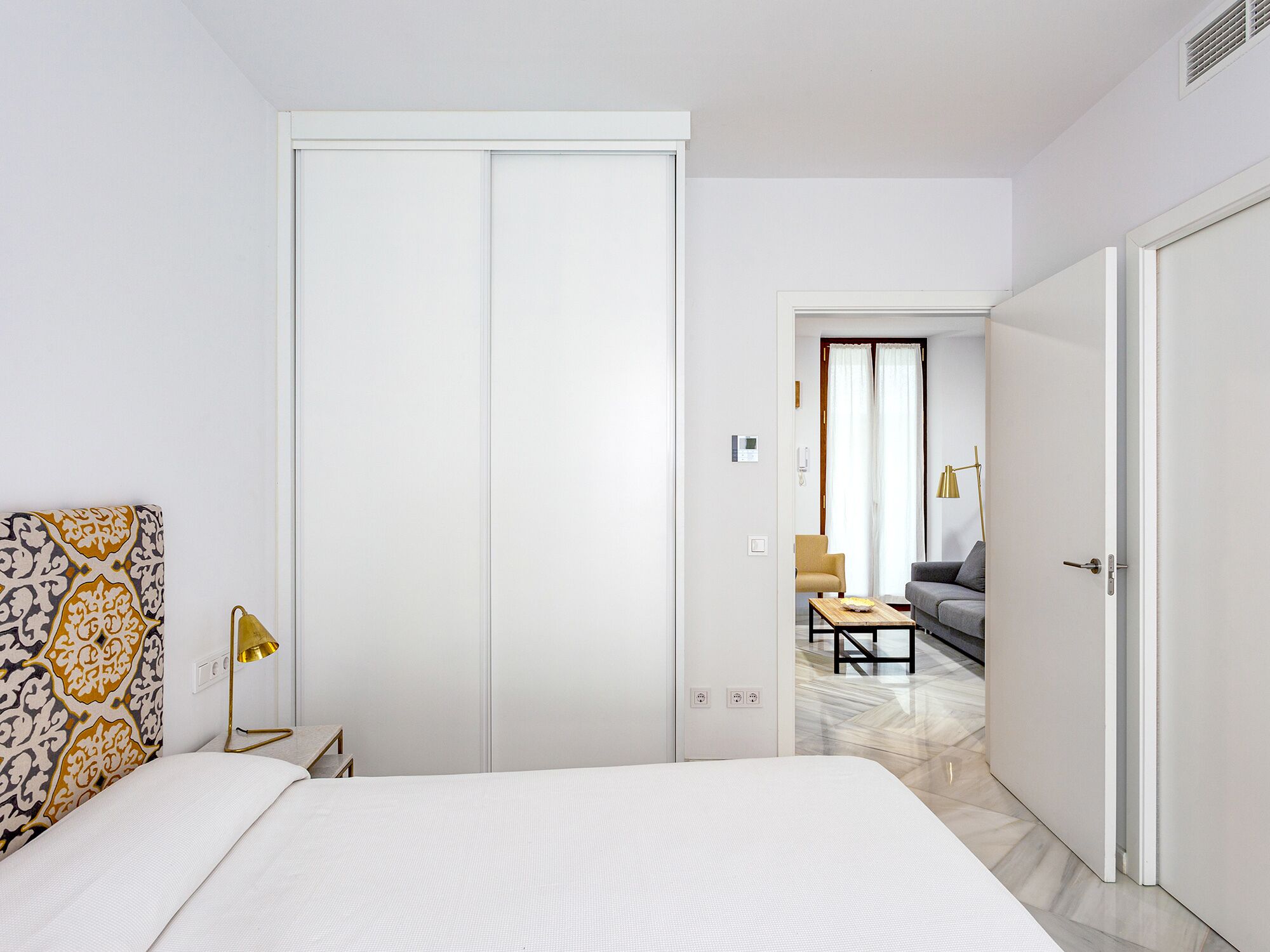 A hotel room with a bed, a wardrobe, a desk, and a chair.