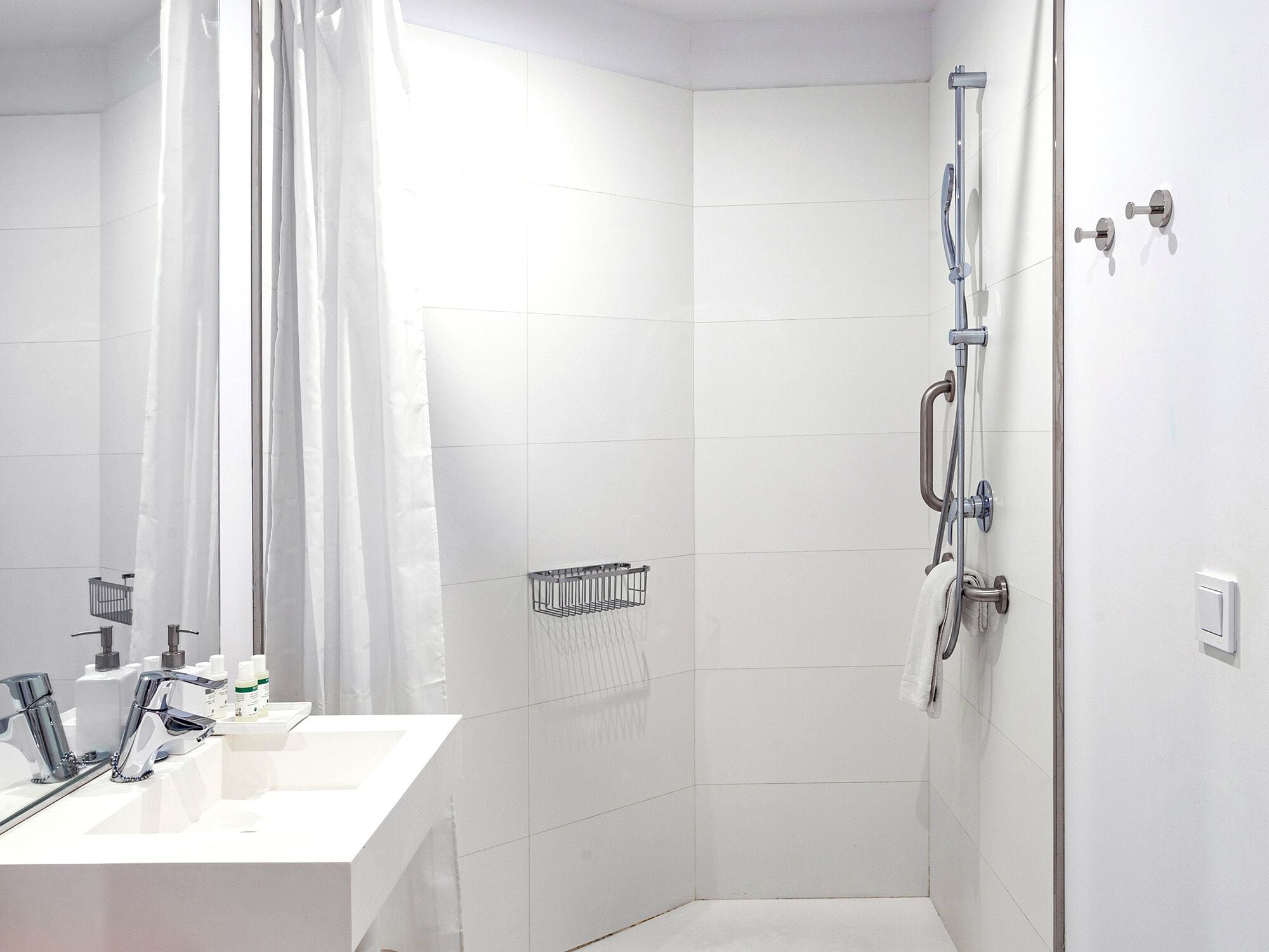 Een moderne badkamer met een douche, wastafel en spiegel.