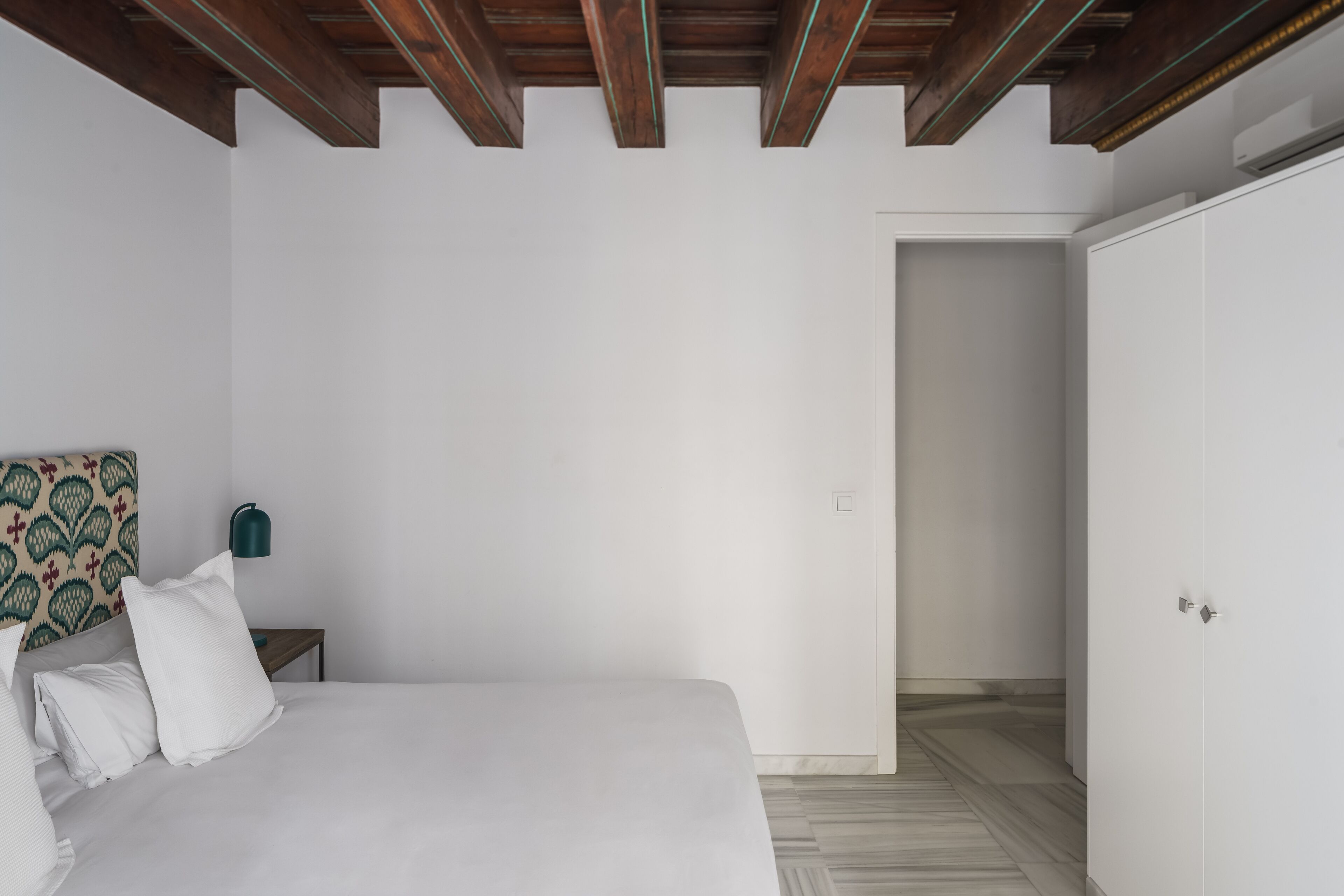 Un dormitorio con una cama, una mesita de noche, una lámpara y un armario.