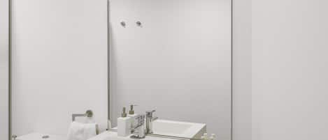 A modern bathroom with a large mirror, two sinks, and a toilet.