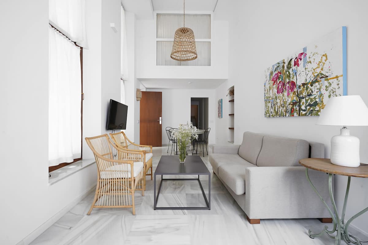 A modern living room with a sofa, coffee table, wicker chairs, and a TV.