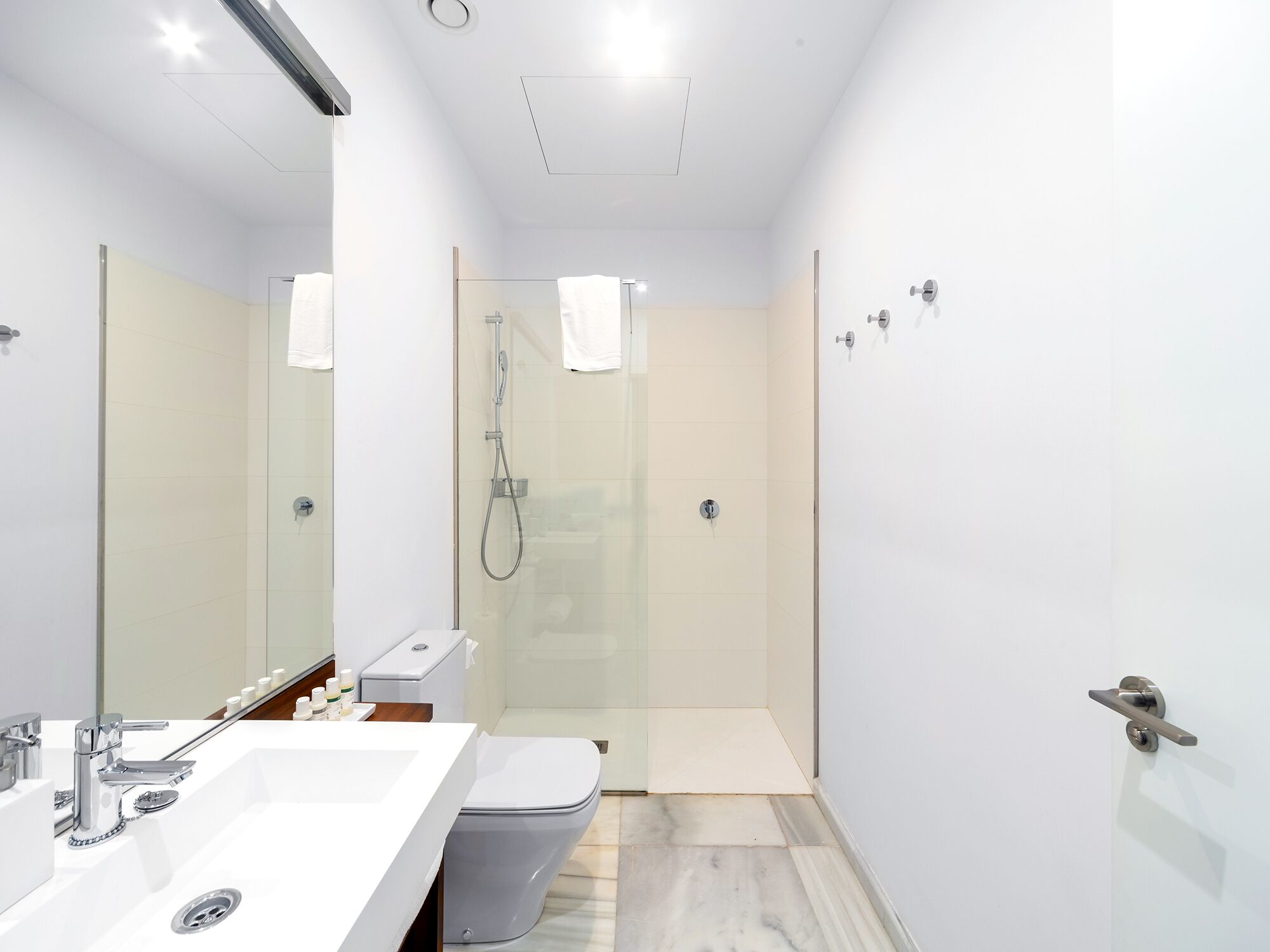 A modern bathroom with a glass-enclosed shower, a white sink with a chrome faucet, and a toilet.